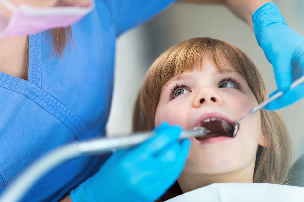 En tannlege utfører arbeid på en liten jentes munn.