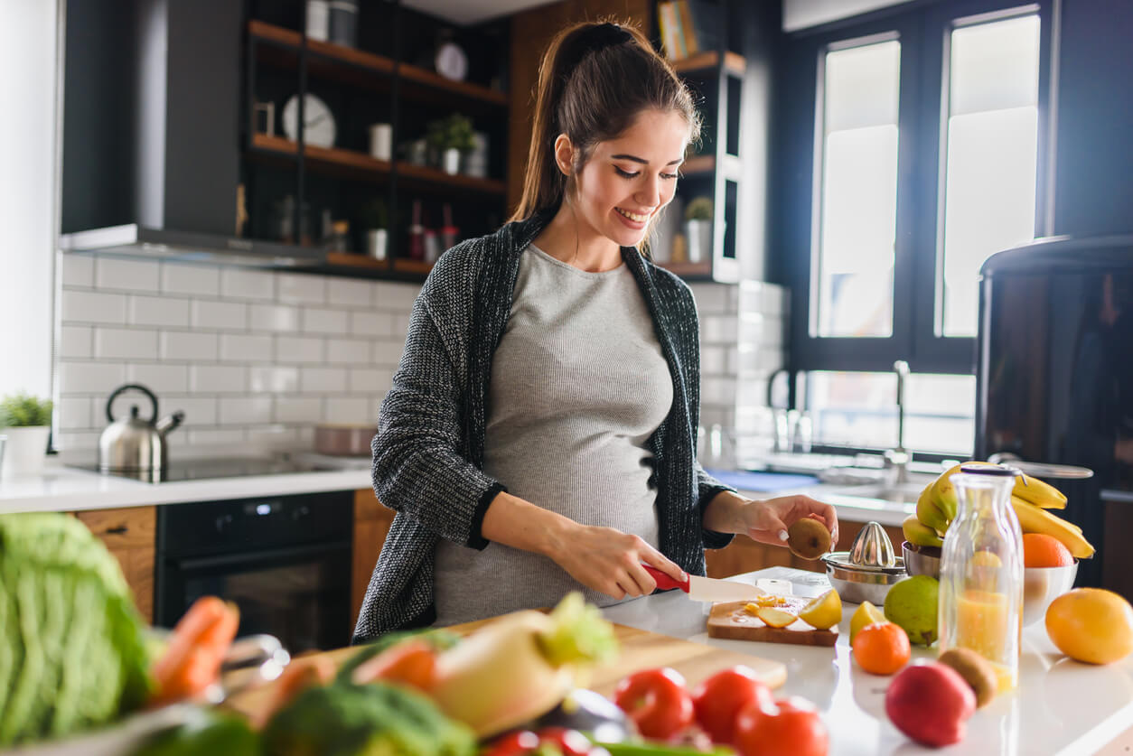 A pregnant woman preparing fruits and vegetables.