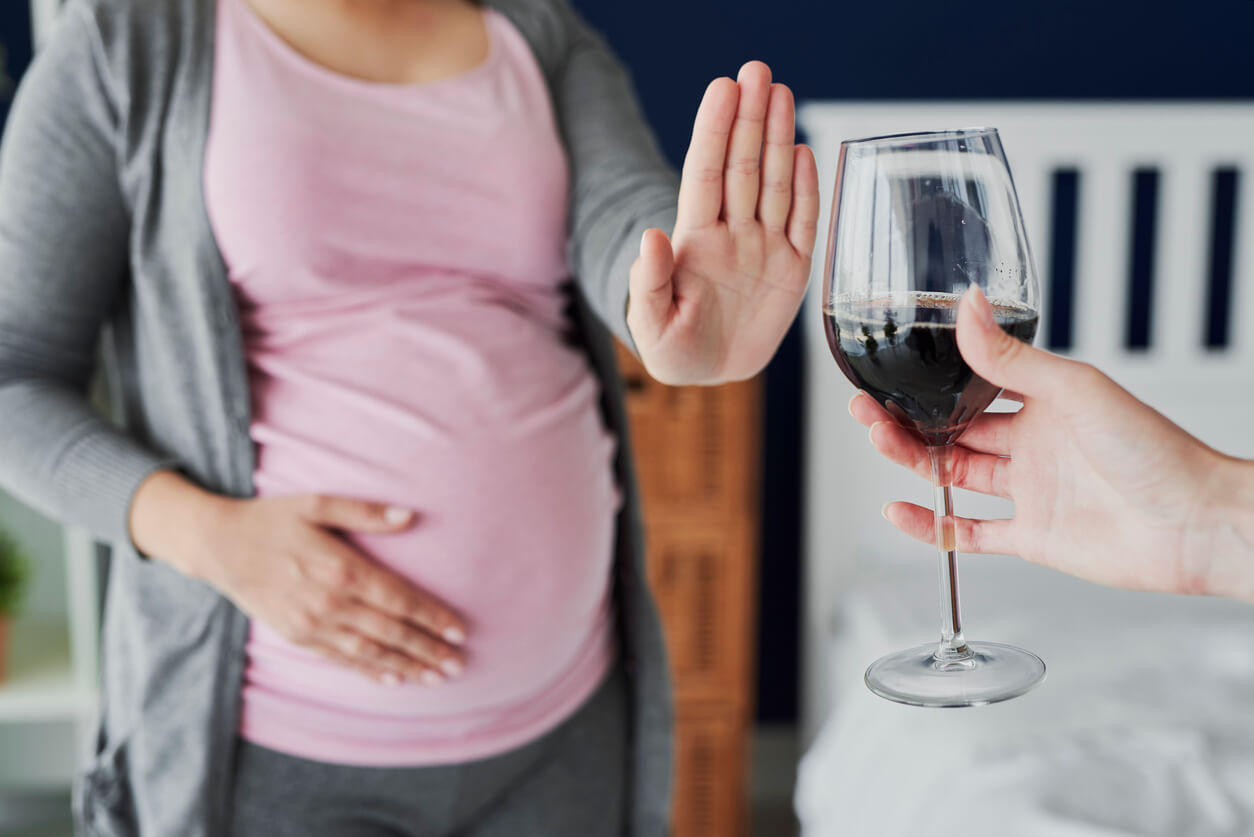 embarazada rechaza dice no copa vino alcohol silla mesa mano stop