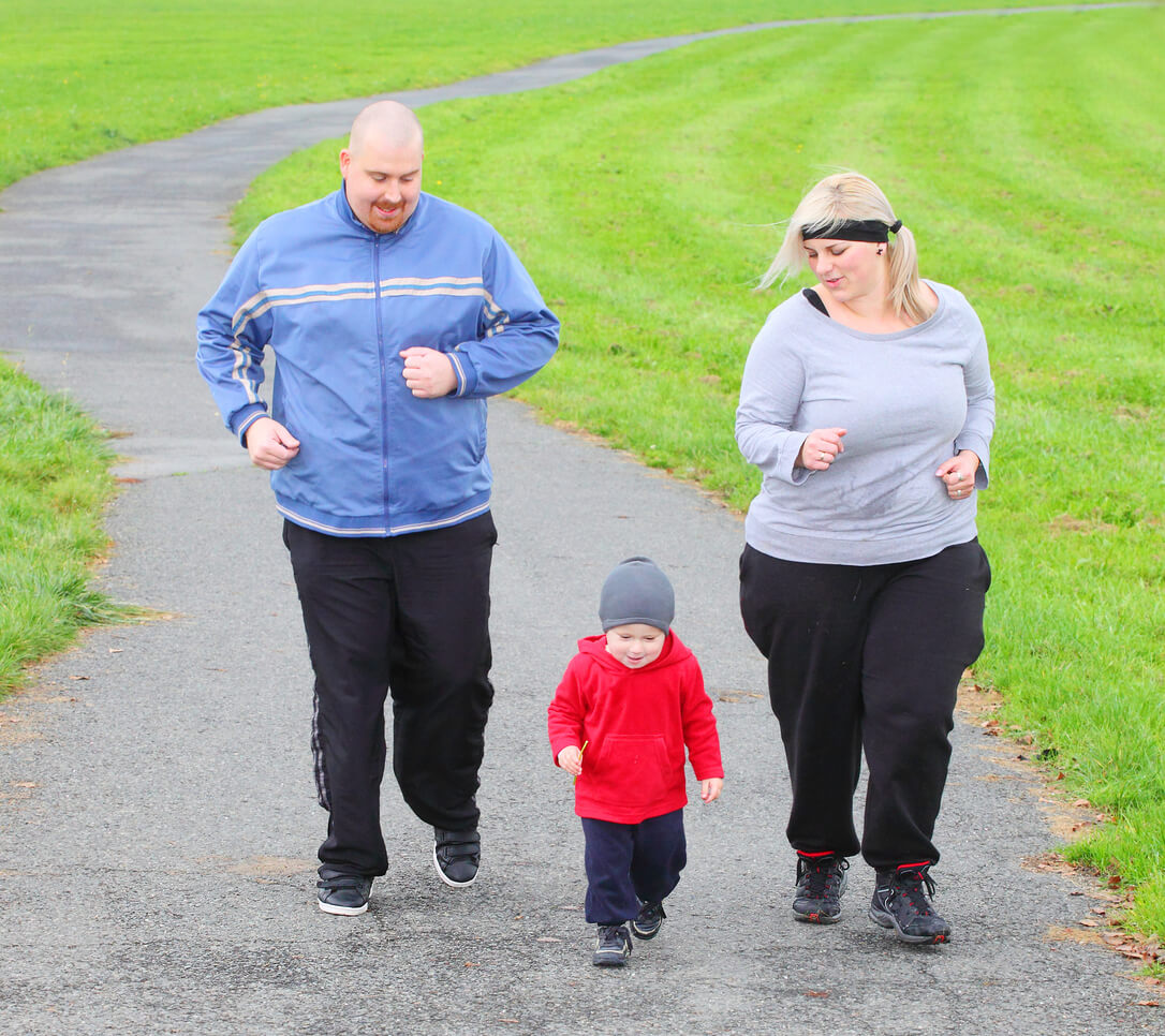 Un papa et une maman avec leur enfant qui marchent.