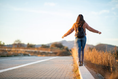 mujer joven adolescente camina de espalda sola costado ruta carretera libre libertad independencia autonomia