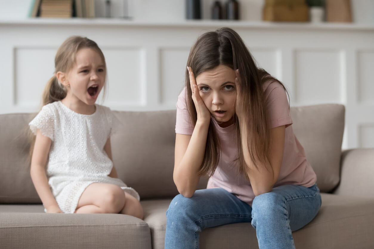 A mother looking overwhelmed as her daughter screams.