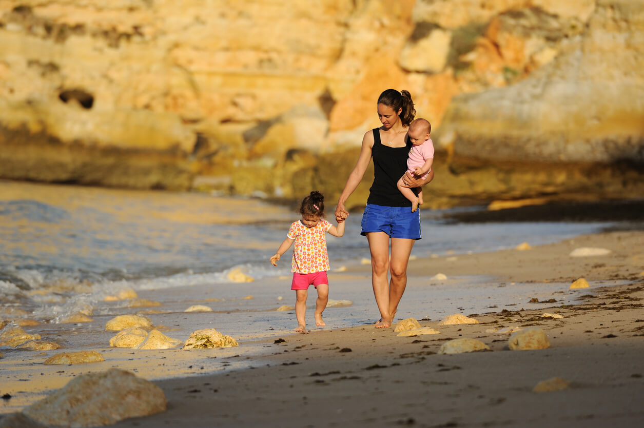 mamma madre cammina spiaggia tramonto figlio bambino estate protezione solare prevenzione lesioni mano upa