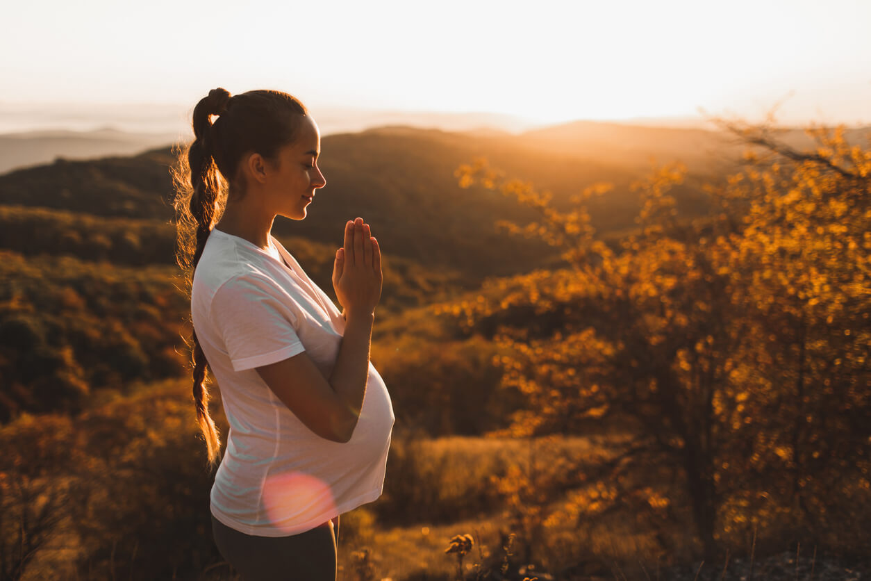 A pregnant woman practicing mindfulness in nature.