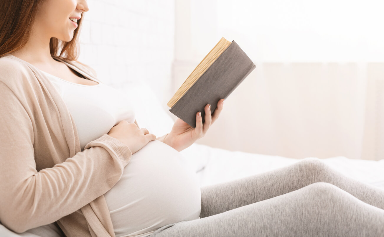 mujer embarazada lee libro informa literatura disfruta placer ocio cultura aprende aprendizaje relajacion sillon tarde dia
