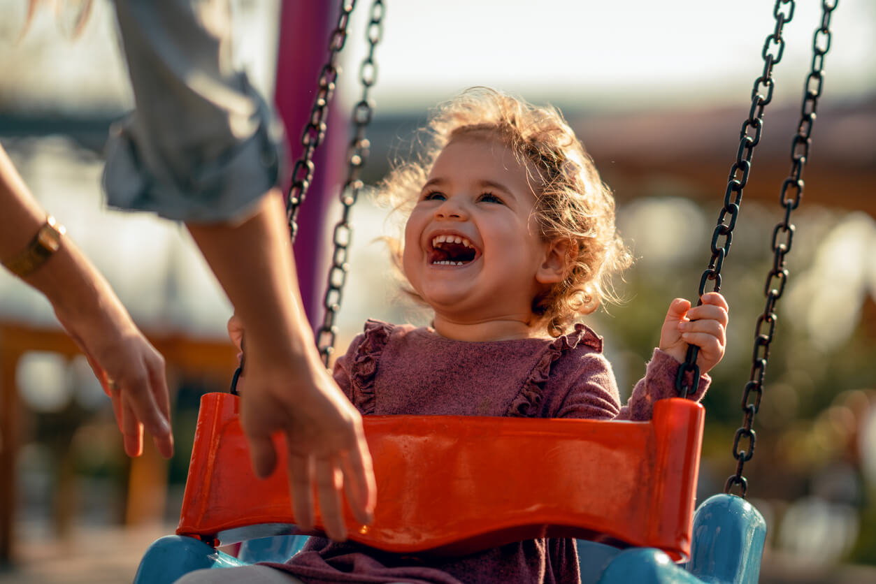 happiness little girl on swing plays with her mother