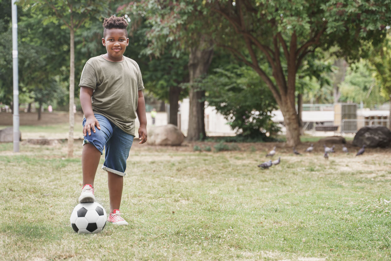 Un enfant en surpoids avec un ballon de football. 