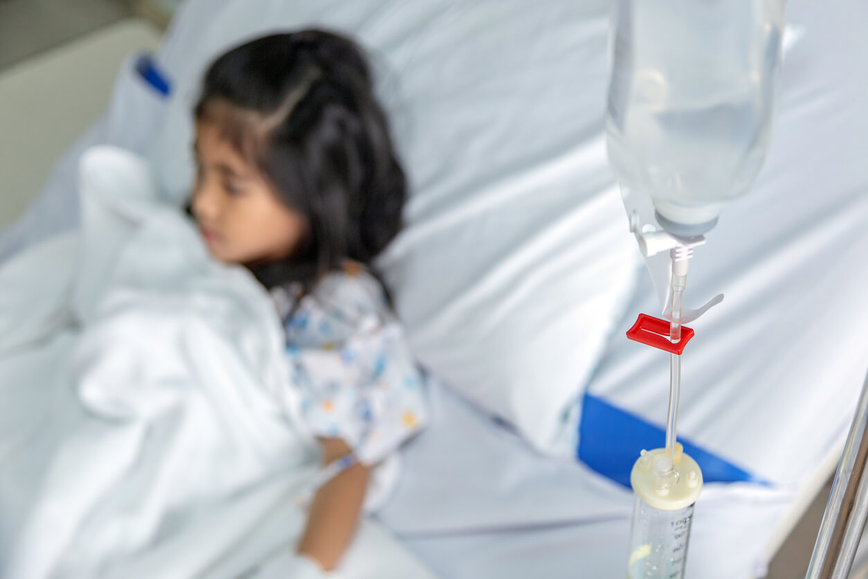 A young girl in a hospital bed connected to an IV.