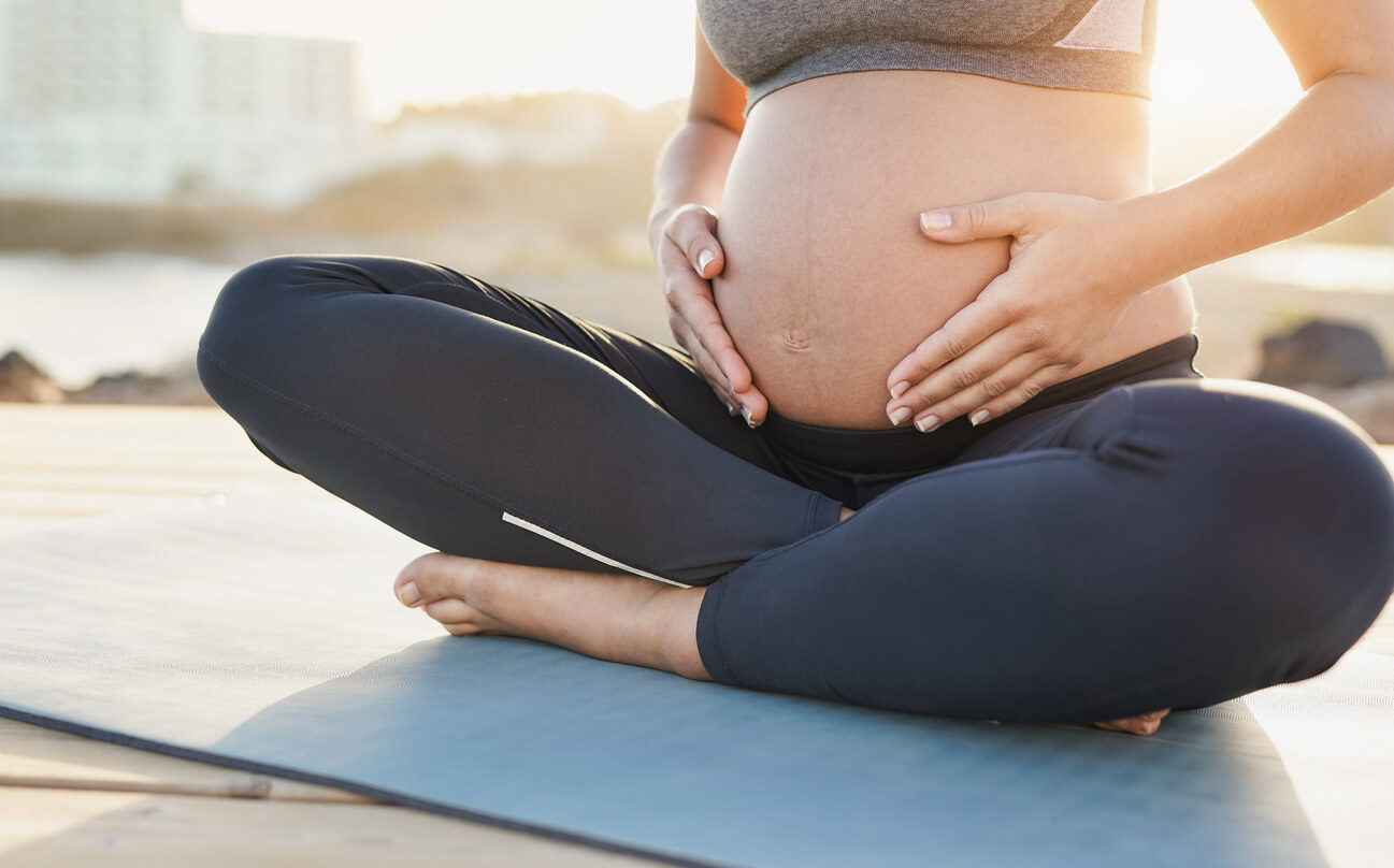 yoga respiracion consciente mujer embarazada sentada mat playa toca vientre panza abdomen