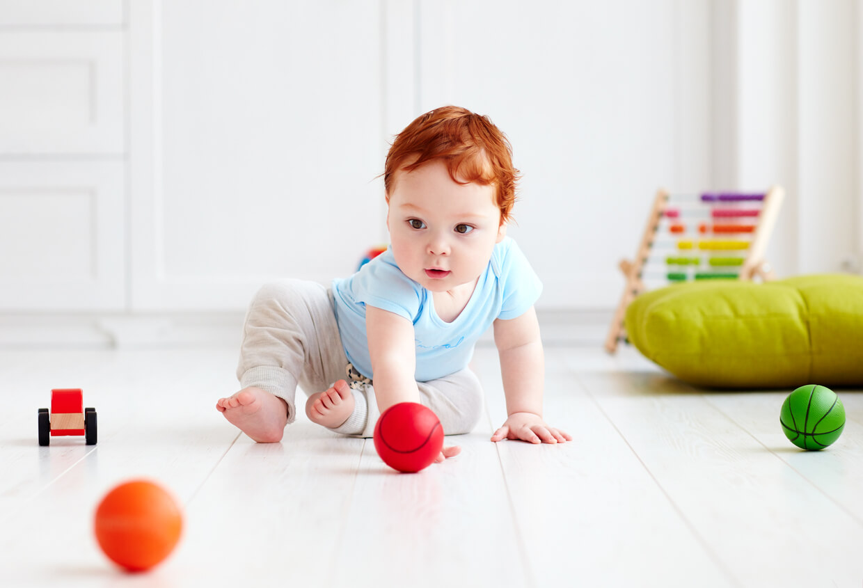 En baby som leker med plastkuler på gulvet.