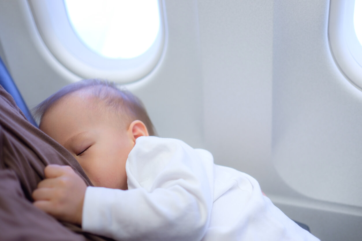 Un bébé qui tète le sein de sa mère dans un avion. 