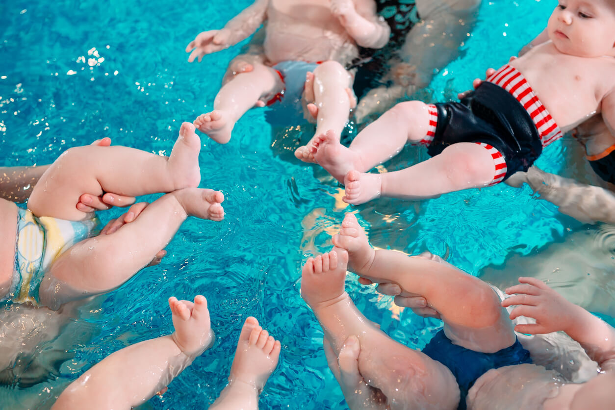 Cinq bébés qui agitent leurs pieds dans l'eau. 