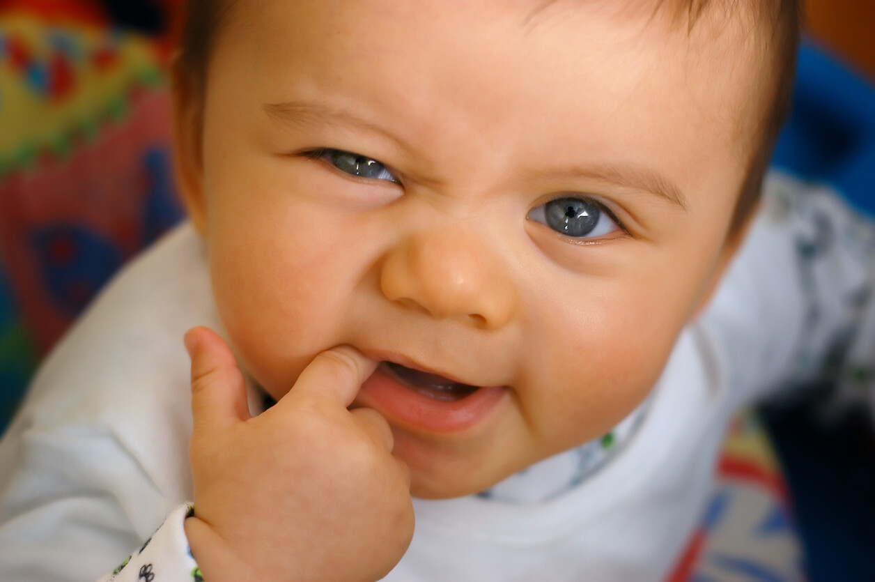 A teething baby chewing on his finger.