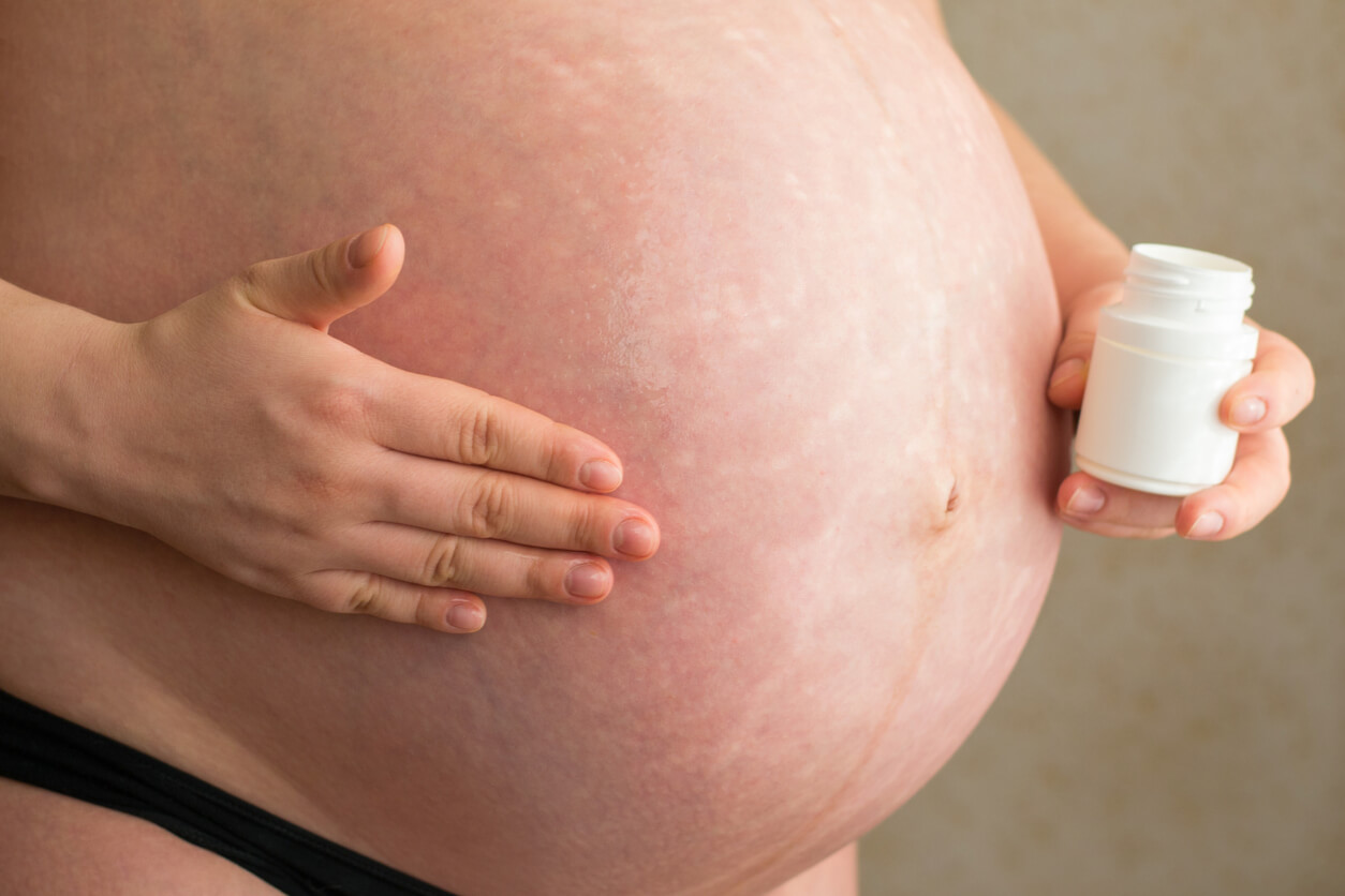 Une femme enceinte qui s'applique de l'huile de coco sur son ventre. 
