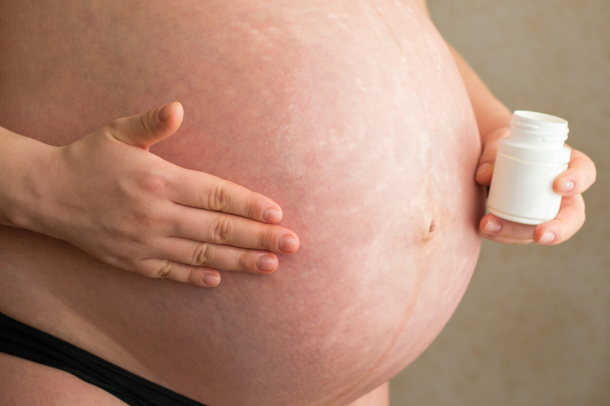 Une femme enceinte qui s'applique de l'huile de coco sur son ventre.