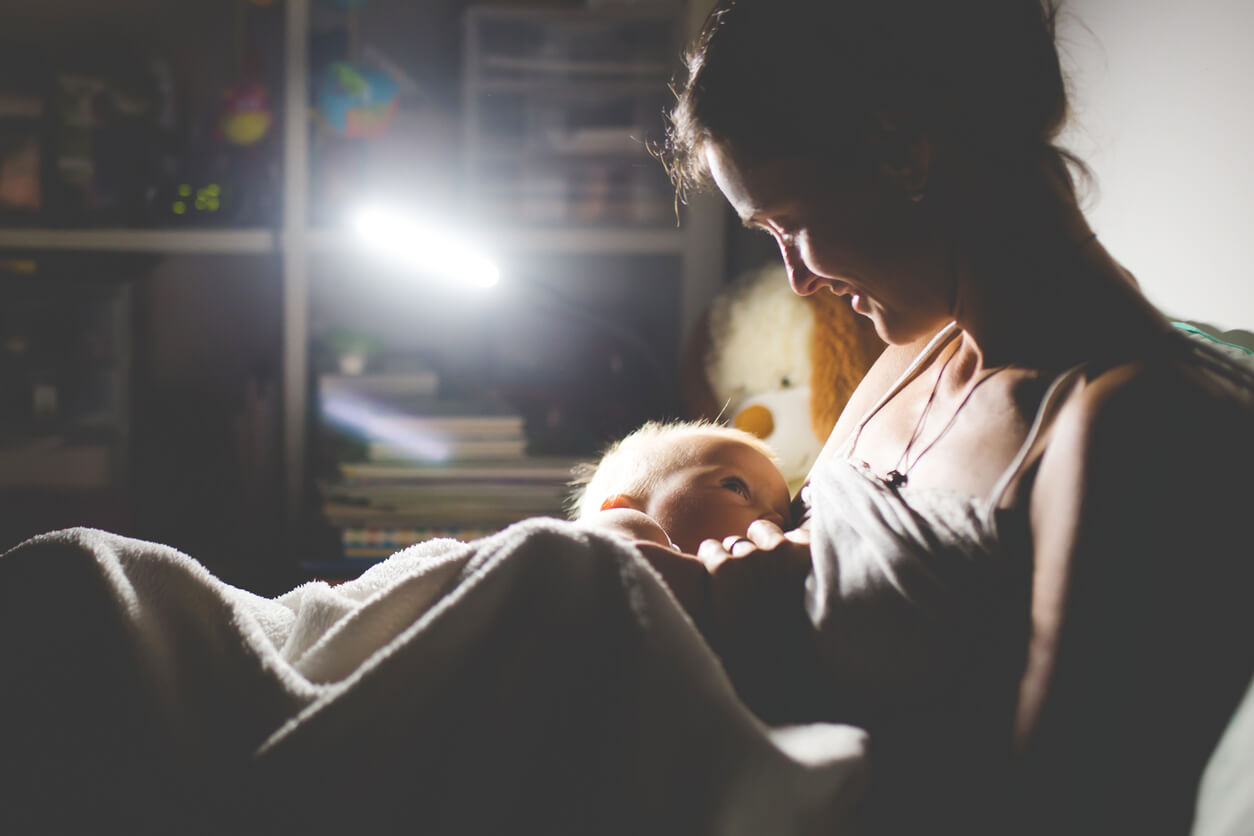 A mother breastfeeding her baby at night.