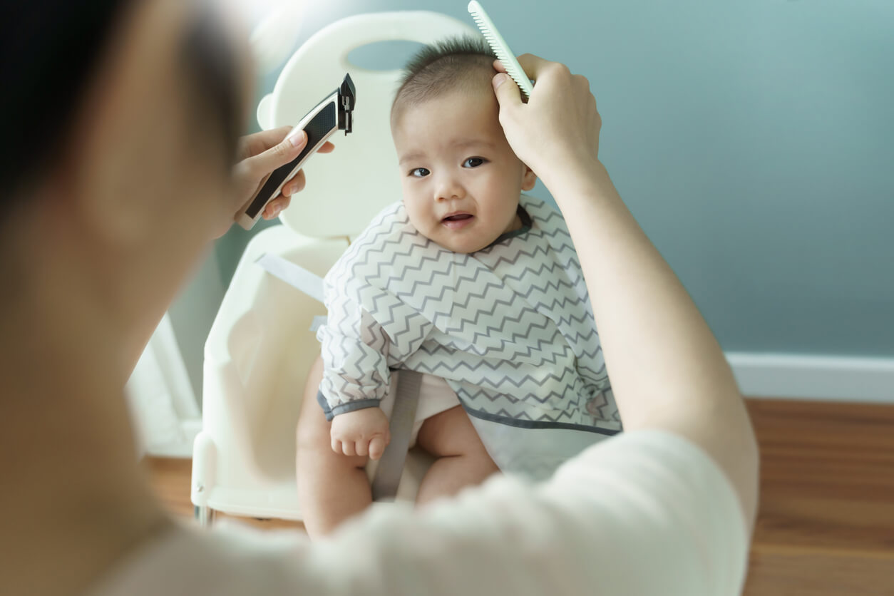 Un adulte qui coupe les cheveux d'un bébé.