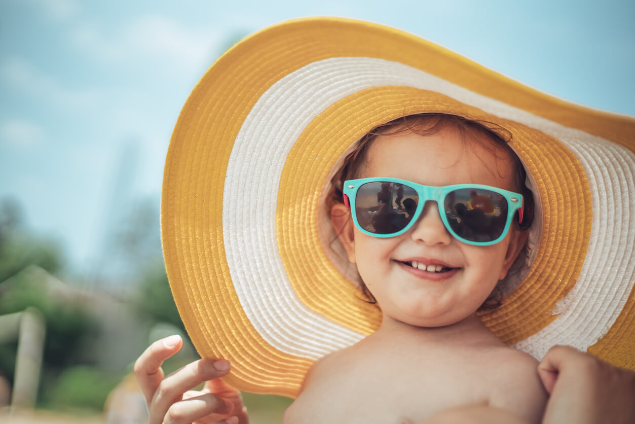 protezione solare da spiaggia fps danni lesioni raggi solari occhiali occhiali da sole cappello a tesa larga spiaggia ragazza bambino felice all'aperto vacanza mare