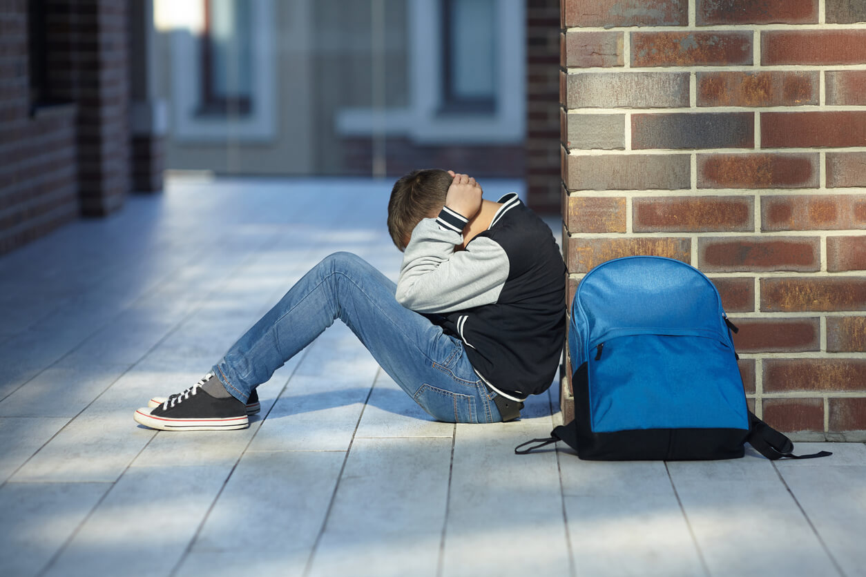 menino chora corredor mochila escolar intimidação depressão sofrendo