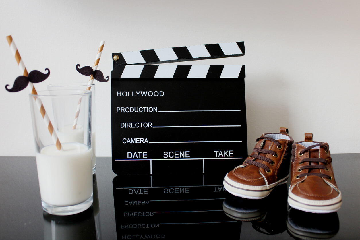 Two glasses of mink, a clapperboard, and a pair of baby shoes.