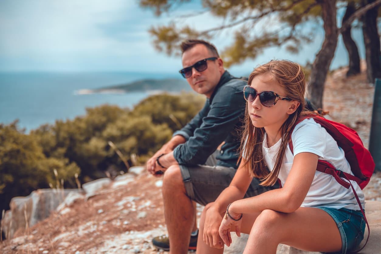 Un père et sa fille qui randonnent au bord de la mer.