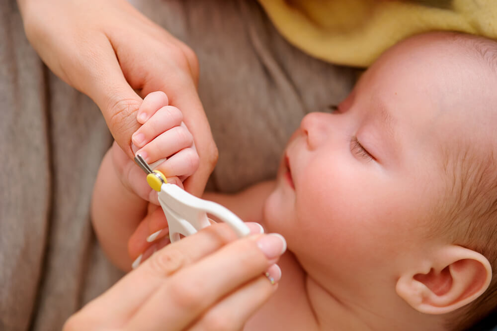 Maman coupant les ongles du bébé.