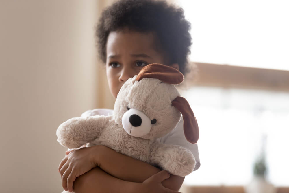 Un enfant avec une peluche dans les bras.