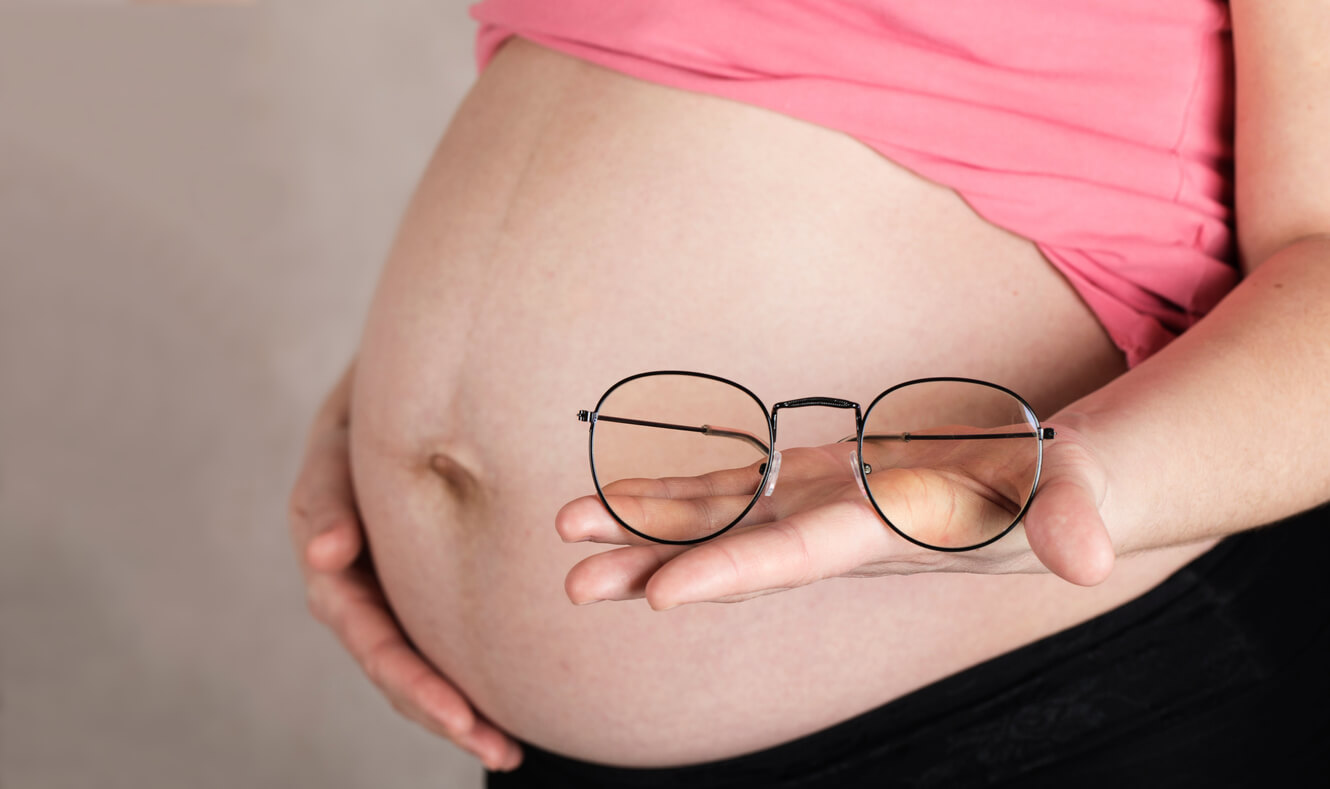 Le ventre d'une femme enceinte avec une paire de lunettes. 