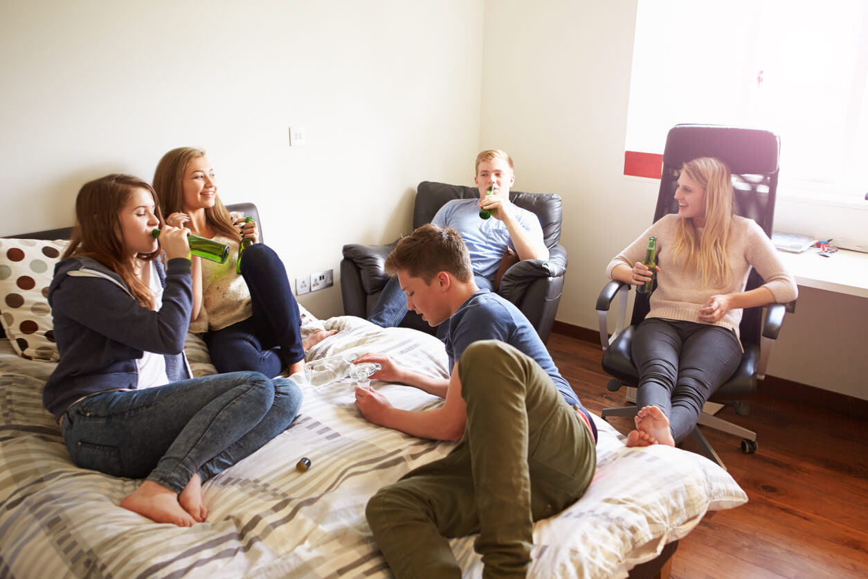 Un groupe d'adolescents qui boivent de l'alcool dans une chambre. 