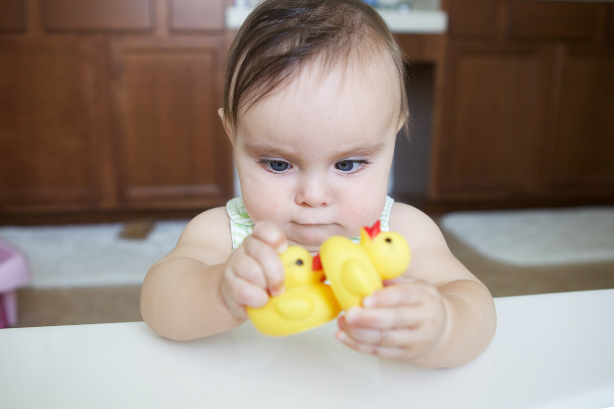 Un bébé souffrant de strabisme qui joue avec un canard en plastique.
