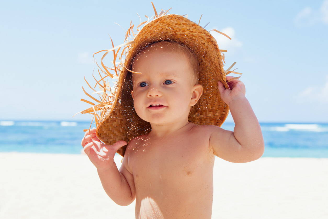 Un enfant sur la plage avec un chapeau.