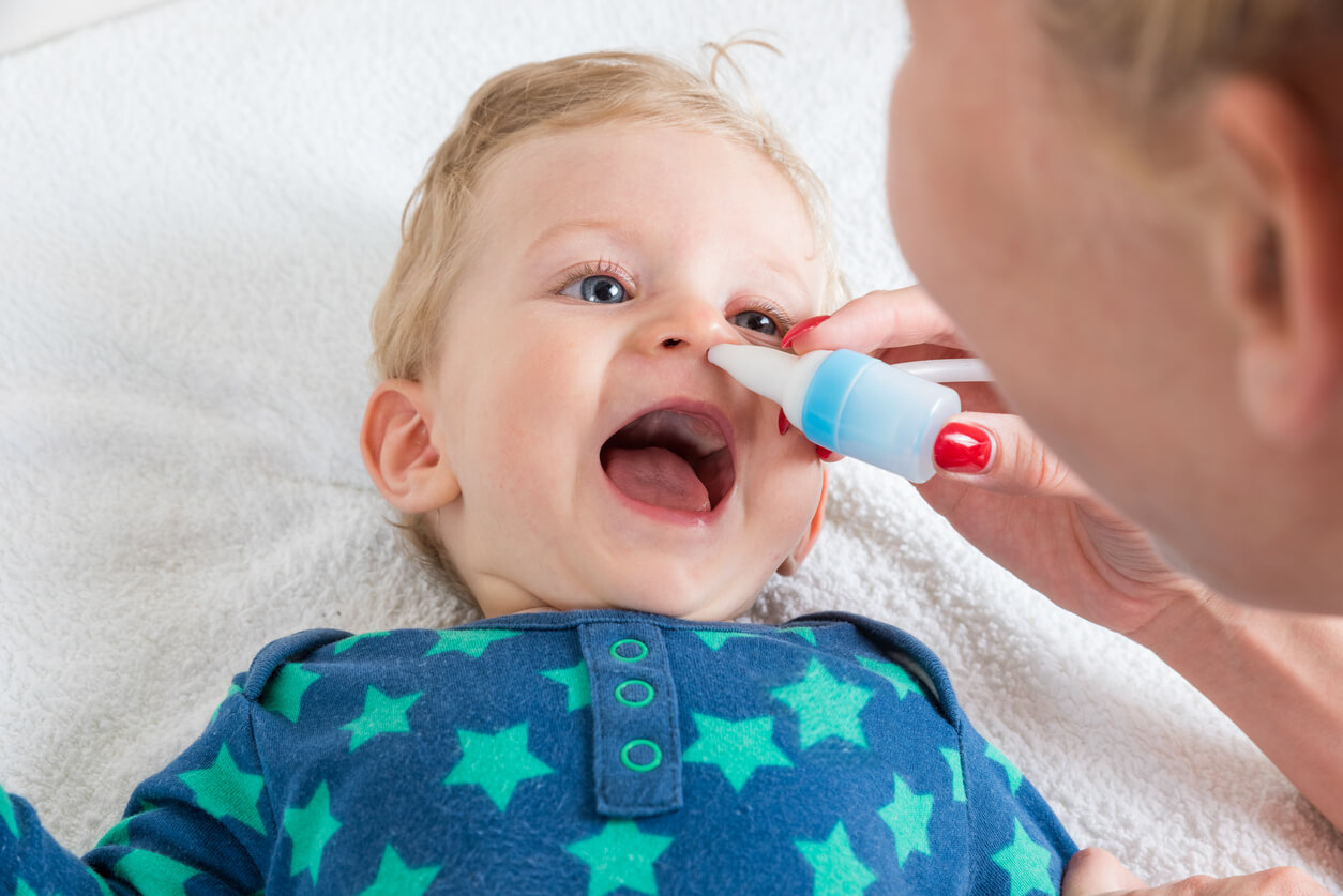 A mother using a nose aspirator on her baby.
