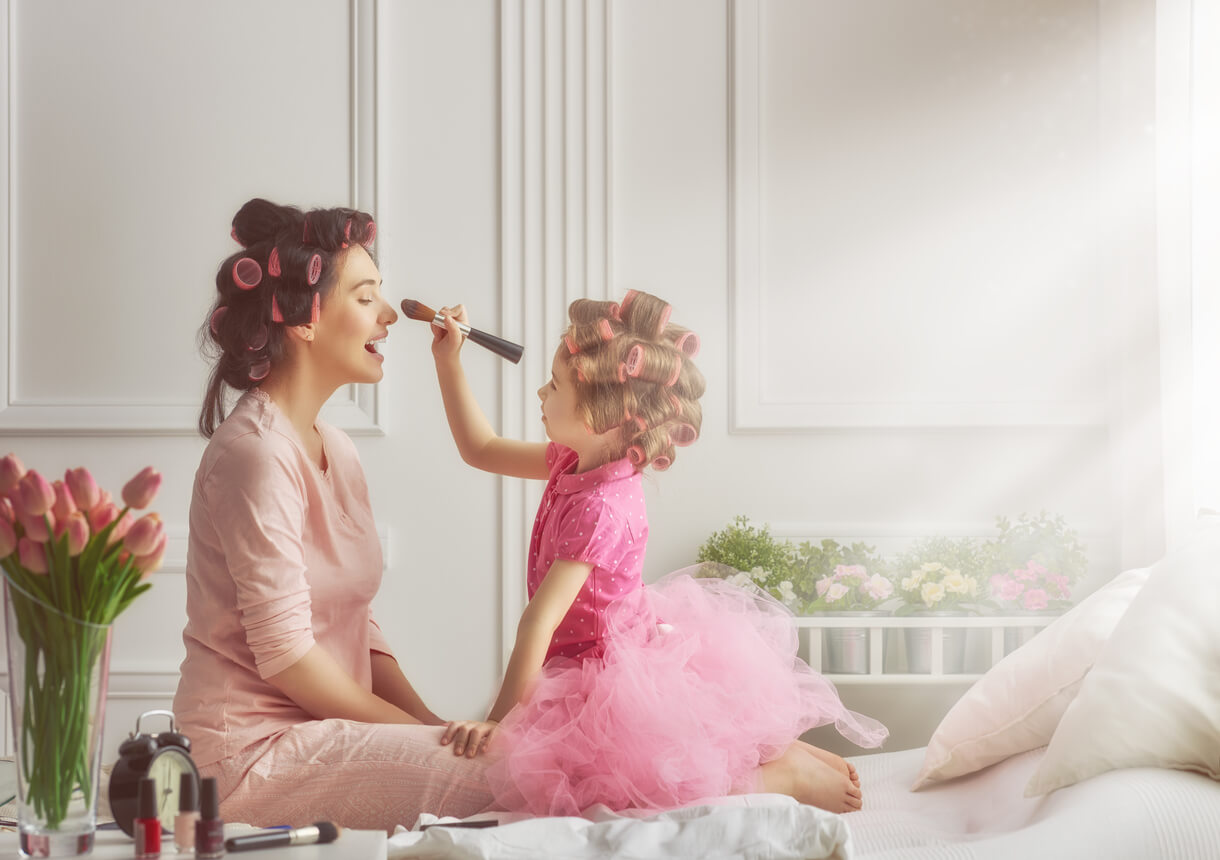 A mother and daughter doing one another's hair and makeup.