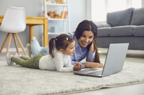 madre e hija ven pelicula computadora portatil piso living casa estar