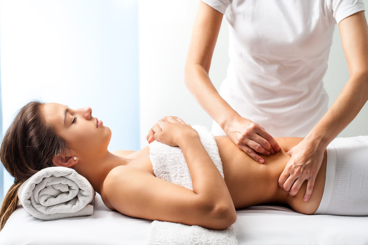 mujer masajista osteopata fisioterapia masaje abdomen curativo dolor mujer acostada