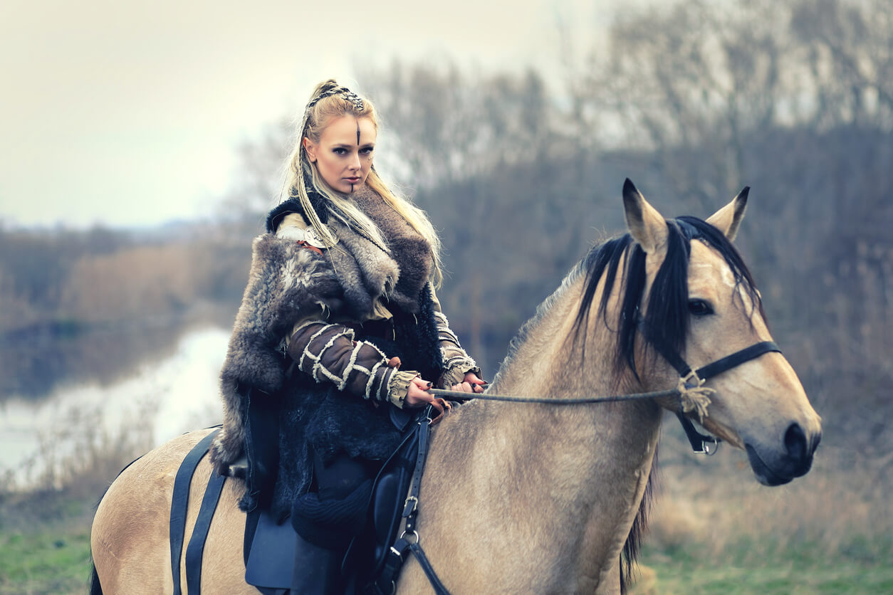 Mulher celta montada em um cavalo na floresta.