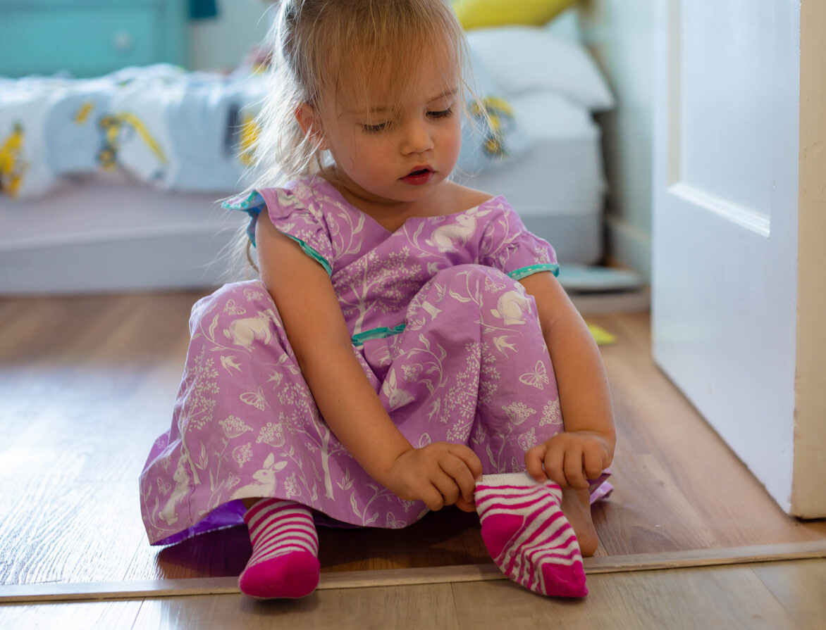 menina calçando meias sozinha autonomia independência desenvolvimento infantil vestido