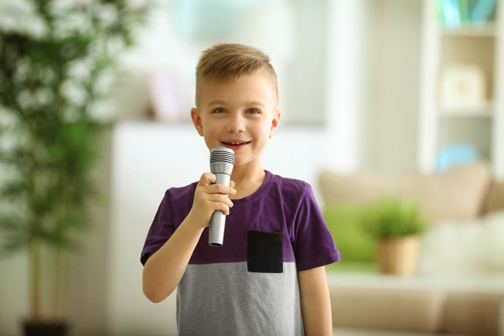 Niño hablando solo mientras juega con un micrófono.