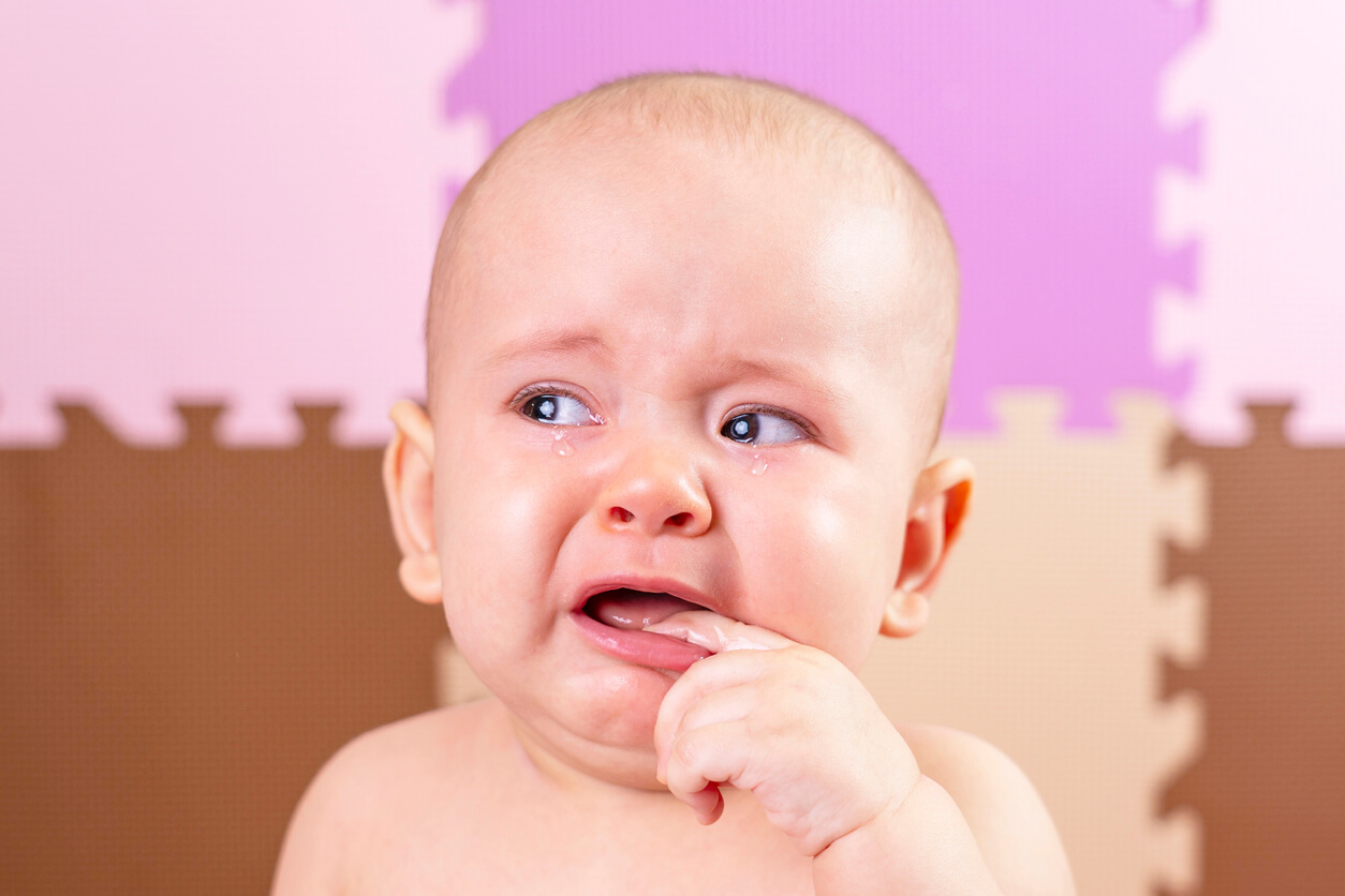 Un bébé qui pleure avec un doigt dans la bouche.