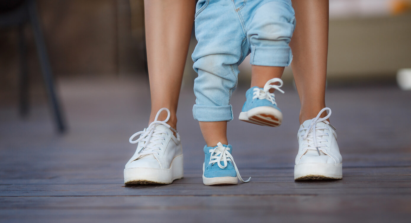 Les pieds d'un enfant et d'un adulte qui marchent ensemble.