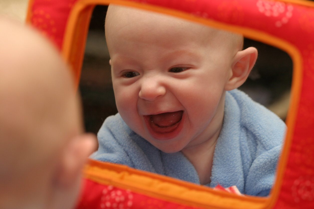 bebe se rie frente al espejo reflejo