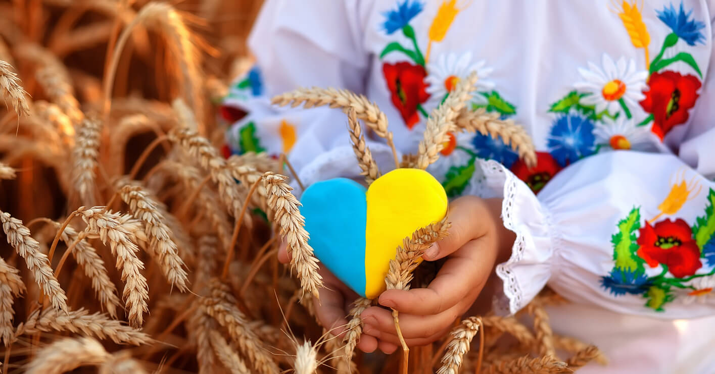 Menina segurando coração com as cores da bandeira ucraniana.