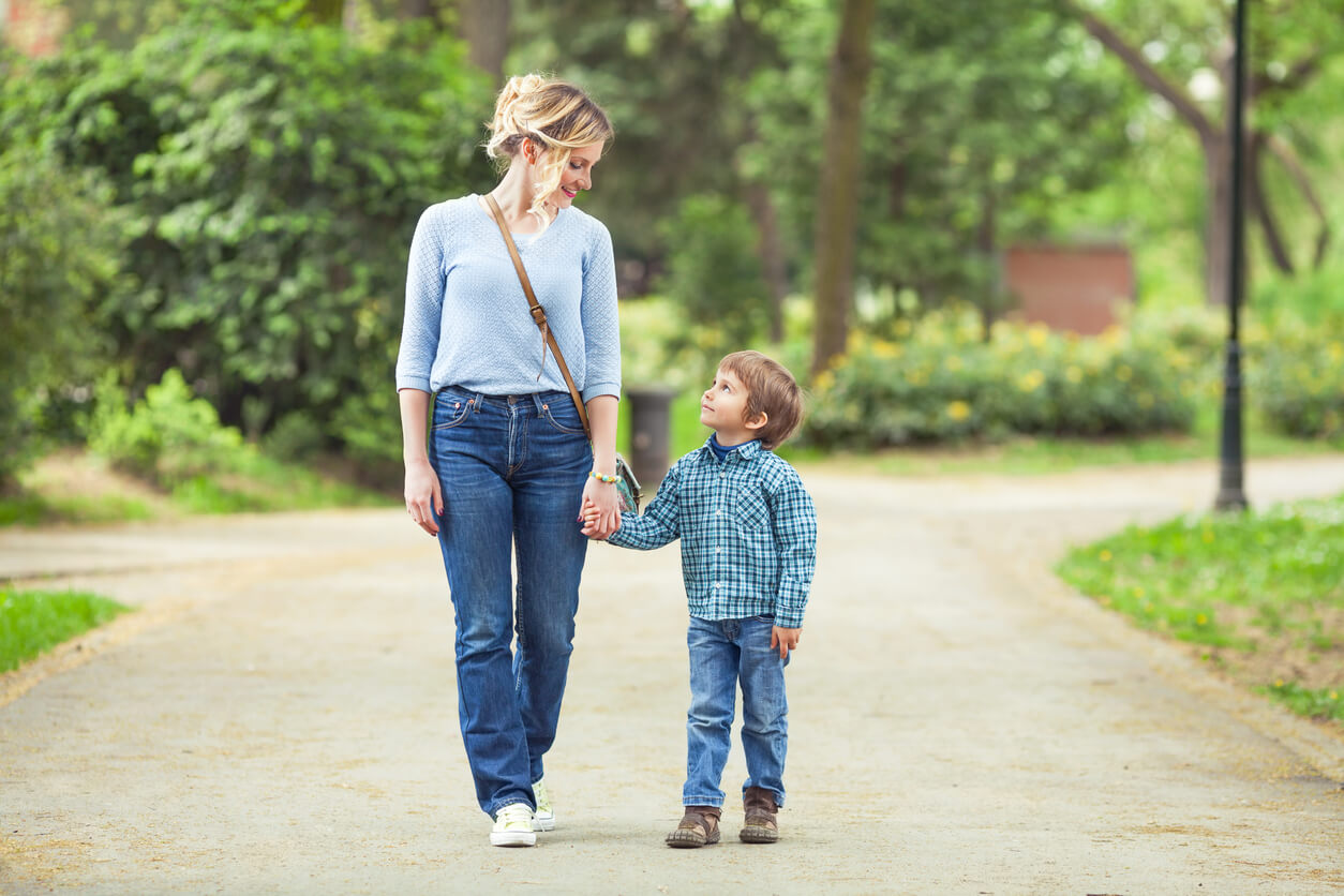 A mother and son walking in the park and looking at one another.