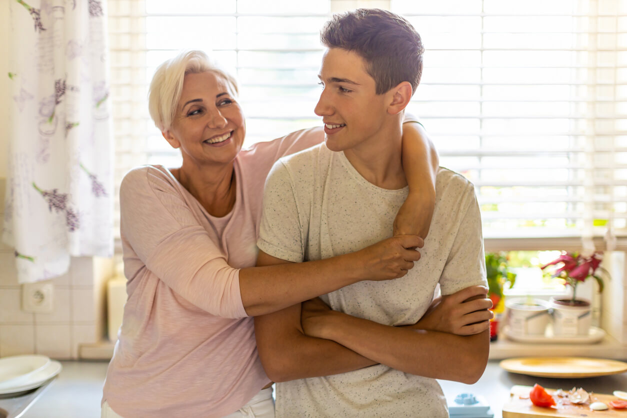 mère embrasse son fils adolescent dans la cuisine à la maison