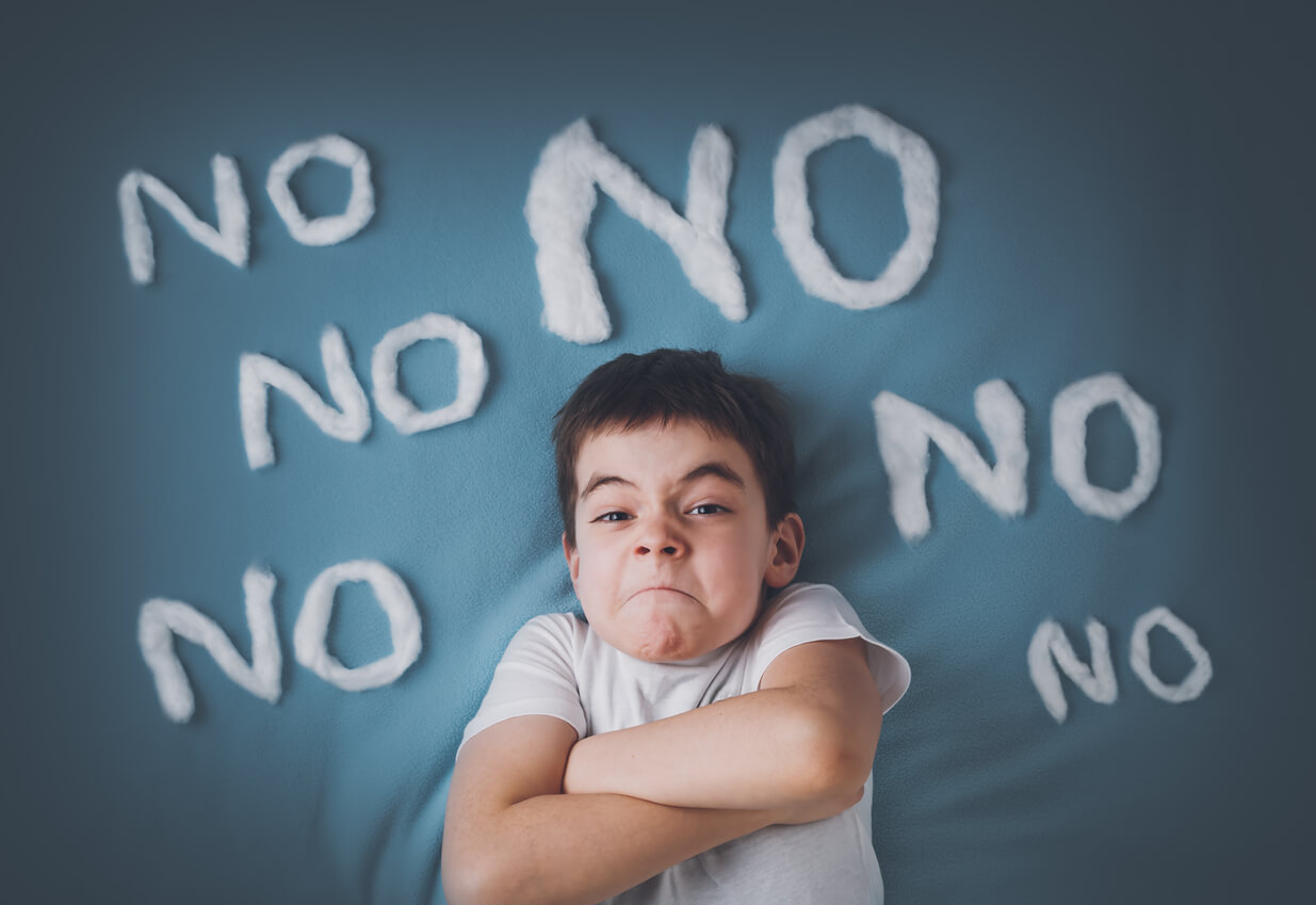 A child crossing his arms surrounded by the word "no".