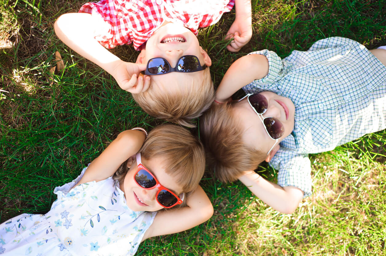 enfants à l'extérieur allongé sur l'herbe heureux lunettes de soleil sombres protection solaire