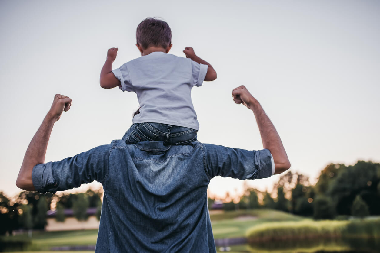 Un père avec son fils sur ses épaules.