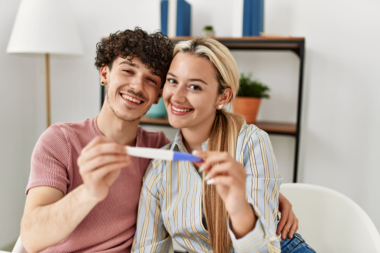 Un jeune couple avec un test de grossesse positif dans la main.