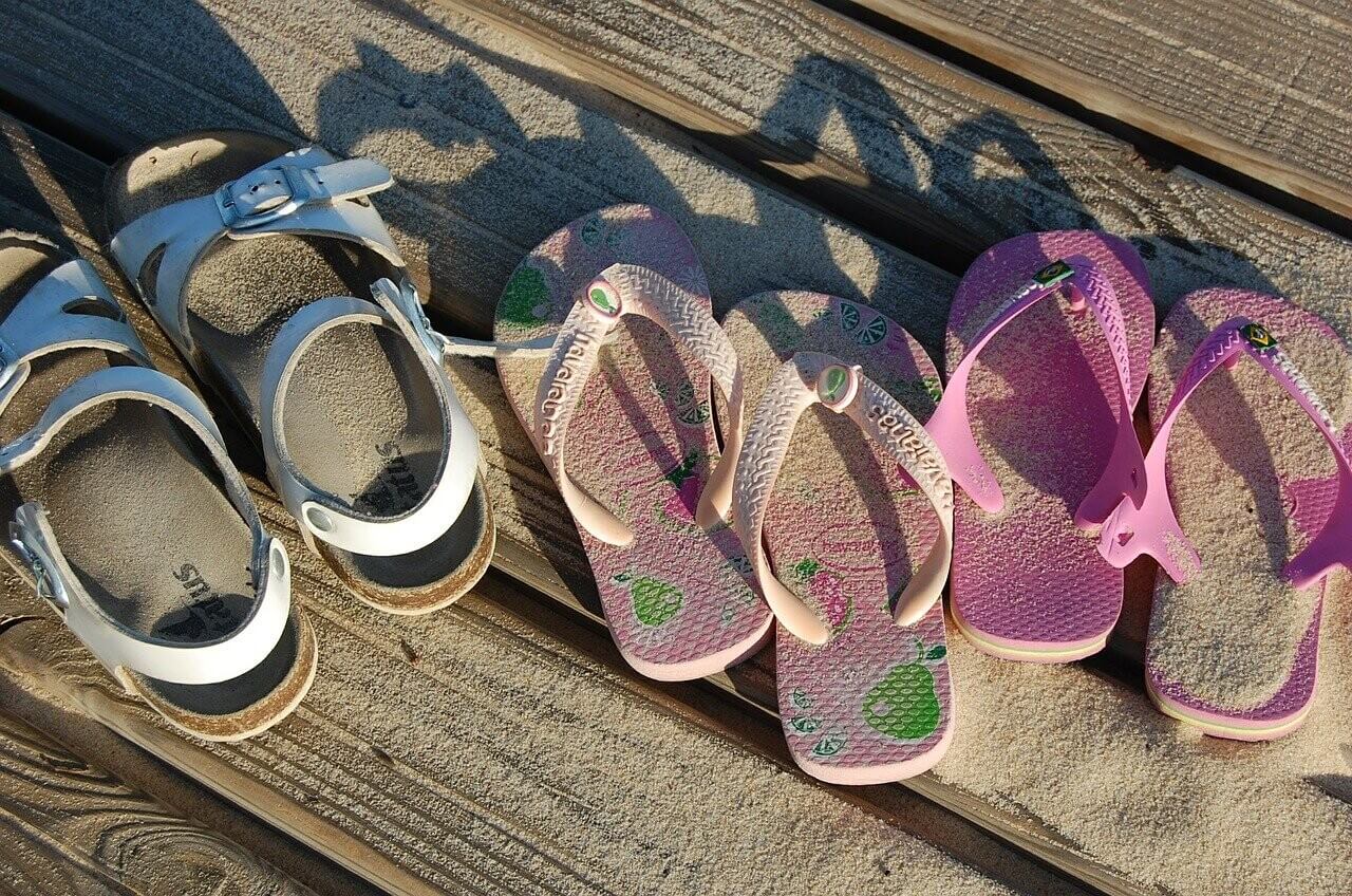 Children's sandals on a sandy deck.