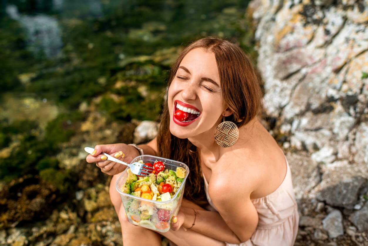 Une jeune femme qui mange une salade dans la nature.